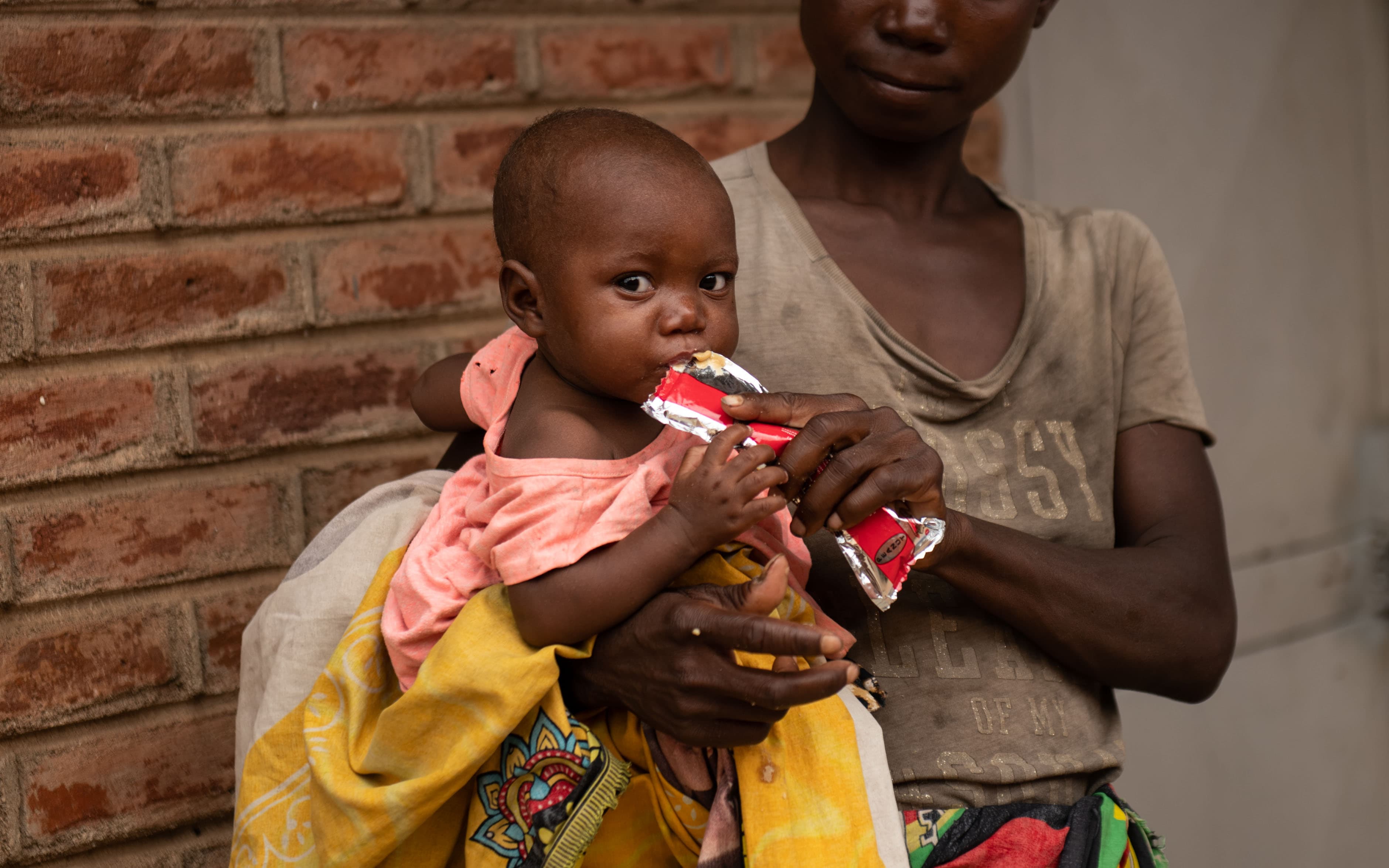 Barn med nötkräm / RUTF - i mammas famn - Malawi 2024 - cropped mobile